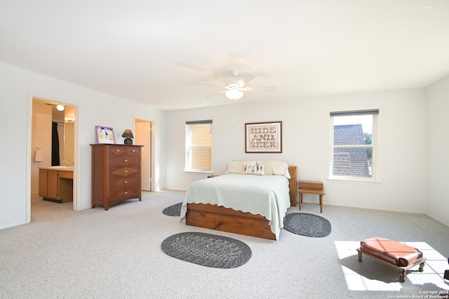 carpeted bedroom with ensuite bath and ceiling fan