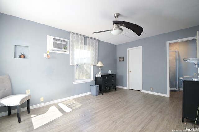 sitting room with a wall unit AC, ceiling fan, and hardwood / wood-style flooring