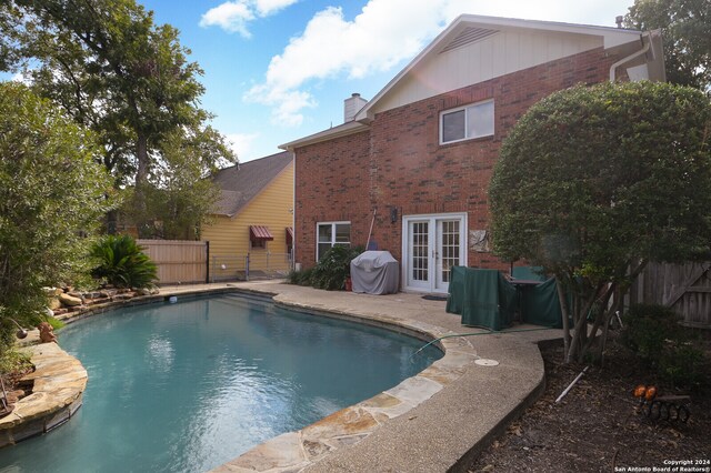 view of pool with french doors and grilling area