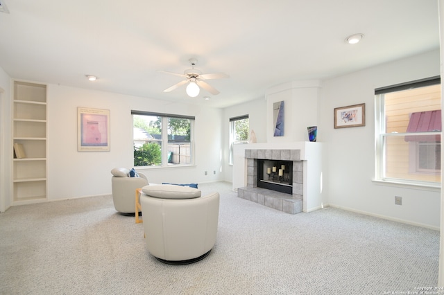 living room featuring a fireplace, light colored carpet, and ceiling fan