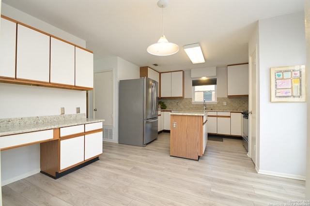 kitchen with white cabinets, appliances with stainless steel finishes, a center island, and light hardwood / wood-style flooring