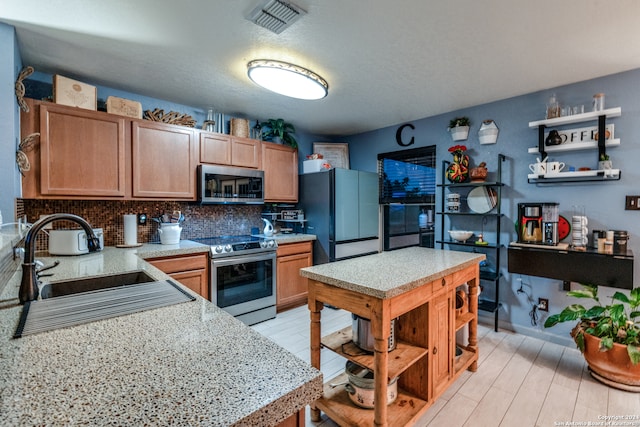 kitchen with appliances with stainless steel finishes, tasteful backsplash, and sink