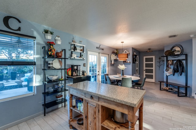 kitchen featuring french doors, pendant lighting, and a textured ceiling