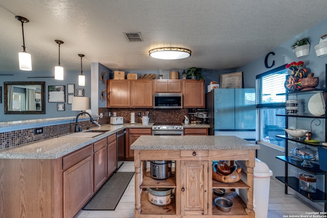 kitchen featuring sink, stainless steel appliances, backsplash, a textured ceiling, and decorative light fixtures