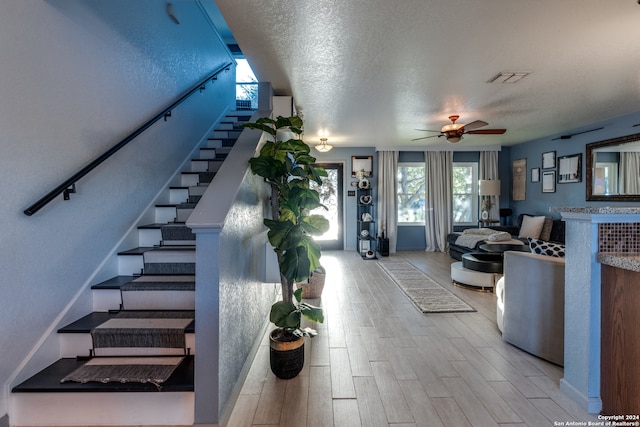 staircase featuring ceiling fan and a textured ceiling