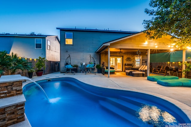 pool at dusk featuring pool water feature, ceiling fan, an outdoor hangout area, and a patio