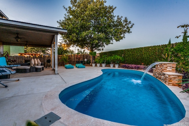 pool at dusk featuring a patio area, ceiling fan, pool water feature, and an outdoor hangout area