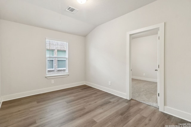 spare room with lofted ceiling and hardwood / wood-style floors