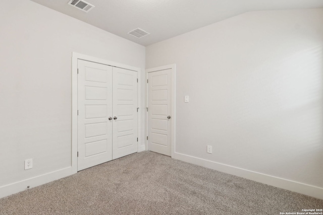 unfurnished bedroom featuring lofted ceiling, carpet floors, and a closet