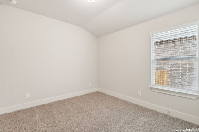 empty room featuring vaulted ceiling and carpet flooring