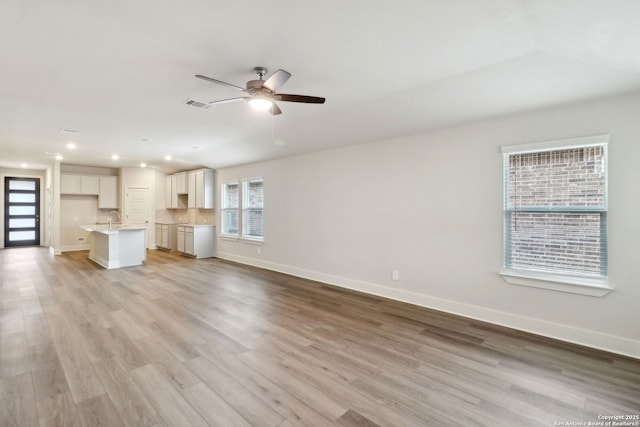 unfurnished living room with ceiling fan, sink, and light hardwood / wood-style floors