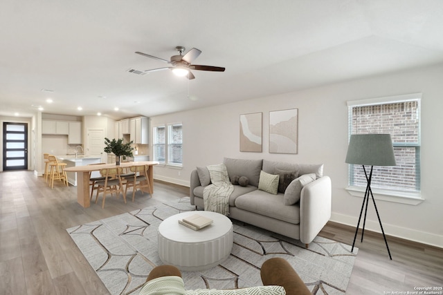 living room featuring sink, light hardwood / wood-style flooring, and ceiling fan