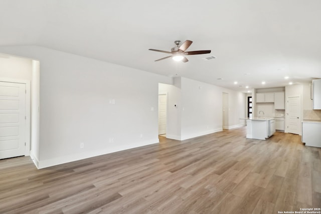 unfurnished living room featuring lofted ceiling, sink, ceiling fan, and light wood-type flooring