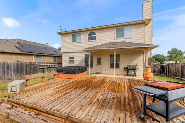 back of house with a wooden deck and a hot tub