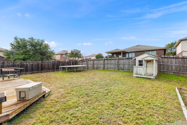 view of yard with a trampoline, a deck, and a storage shed