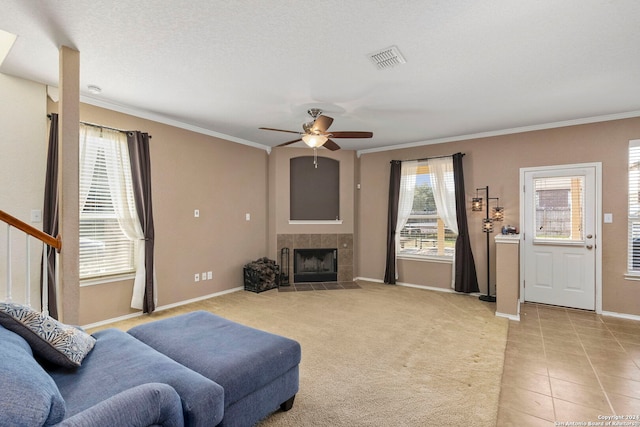 tiled living room with a textured ceiling, ceiling fan, crown molding, and a tile fireplace