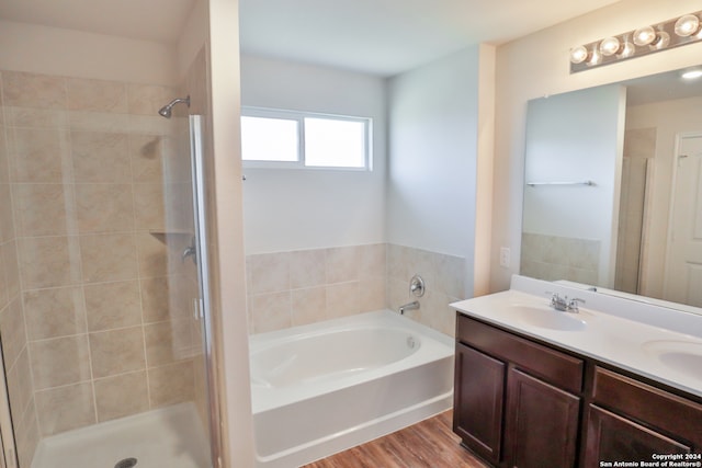 bathroom with hardwood / wood-style floors, vanity, and independent shower and bath