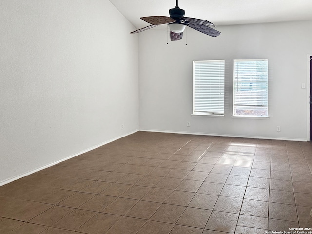 empty room with dark tile patterned flooring, ceiling fan, and lofted ceiling