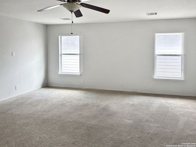 unfurnished room with ceiling fan, light colored carpet, and a textured ceiling