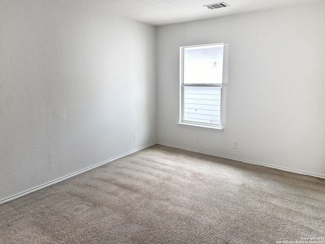 carpeted empty room with a textured ceiling