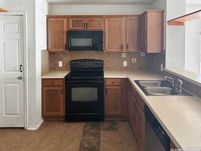 kitchen with decorative backsplash, sink, dark tile patterned flooring, and black appliances