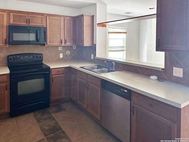 kitchen with tasteful backsplash, a textured ceiling, dark tile patterned floors, sink, and black appliances