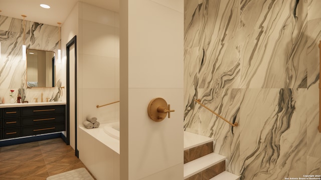 bathroom featuring tiled tub, vanity, and parquet flooring