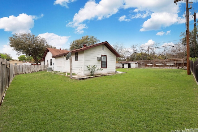 exterior space with a wall mounted air conditioner, a yard, and central AC