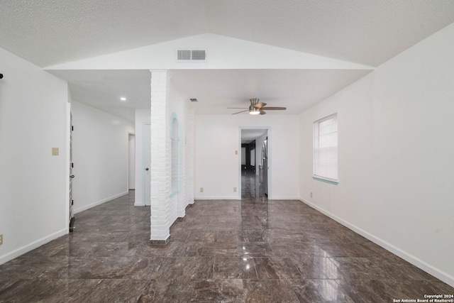 spare room with a textured ceiling, decorative columns, vaulted ceiling, and ceiling fan