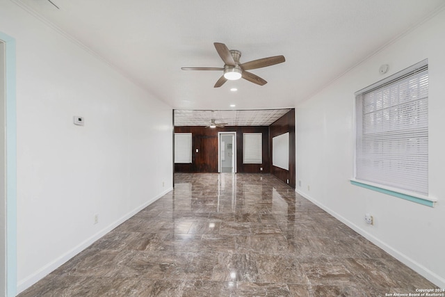 spare room featuring ceiling fan, crown molding, and wooden walls