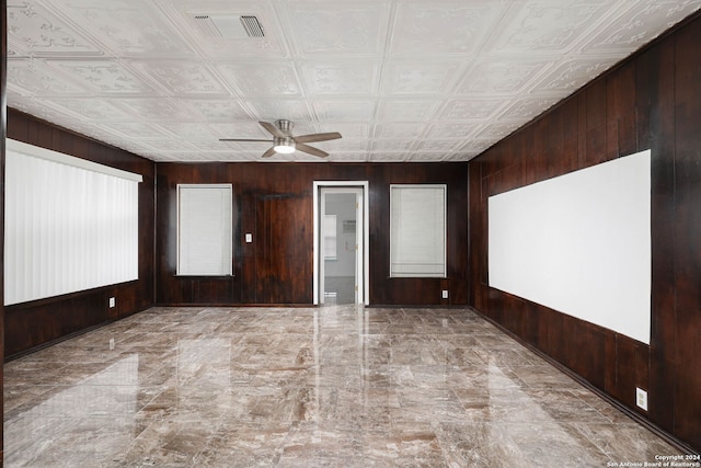 unfurnished room featuring ceiling fan and wood walls