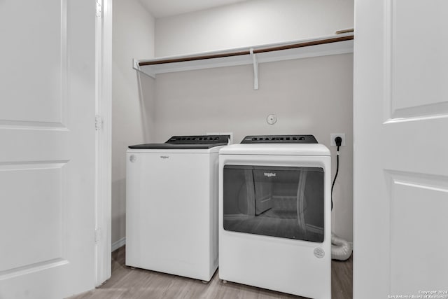 clothes washing area with washing machine and dryer and light hardwood / wood-style floors