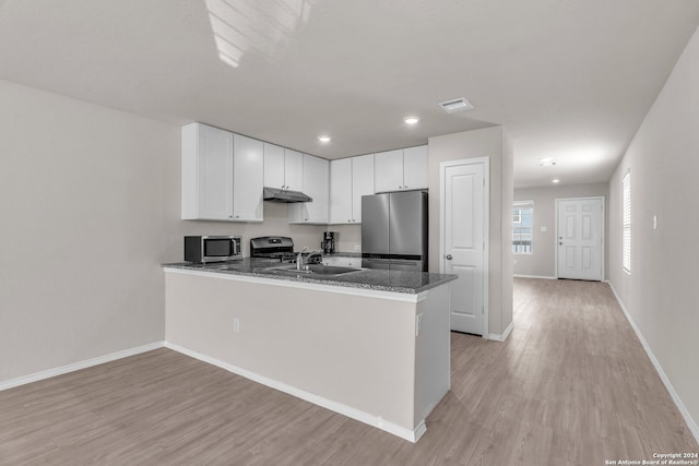 kitchen featuring kitchen peninsula, dark stone countertops, light hardwood / wood-style floors, white cabinetry, and stainless steel appliances