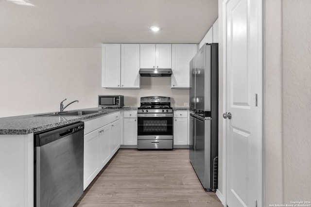 kitchen with kitchen peninsula, stainless steel appliances, white cabinetry, and light hardwood / wood-style flooring