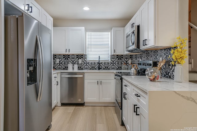 kitchen with sink, stainless steel appliances, backsplash, white cabinets, and light wood-type flooring