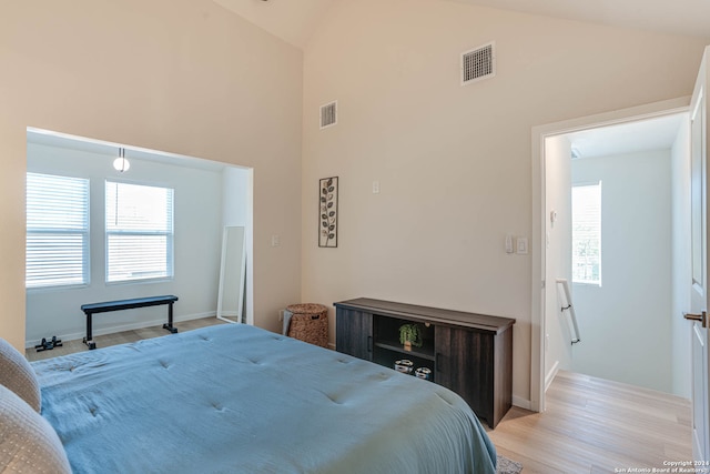 bedroom featuring high vaulted ceiling and light hardwood / wood-style floors