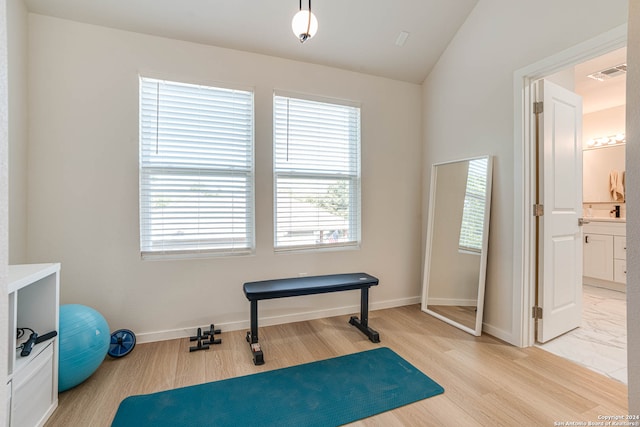 exercise room featuring light hardwood / wood-style floors and lofted ceiling