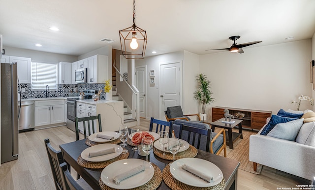 dining space featuring light wood-type flooring, ceiling fan, and sink