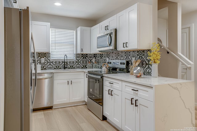 kitchen with white cabinetry, sink, stainless steel appliances, and light stone counters