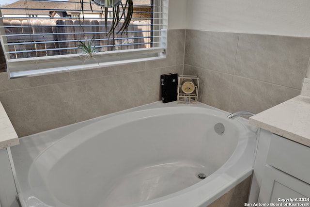 bathroom with vanity and tiled tub