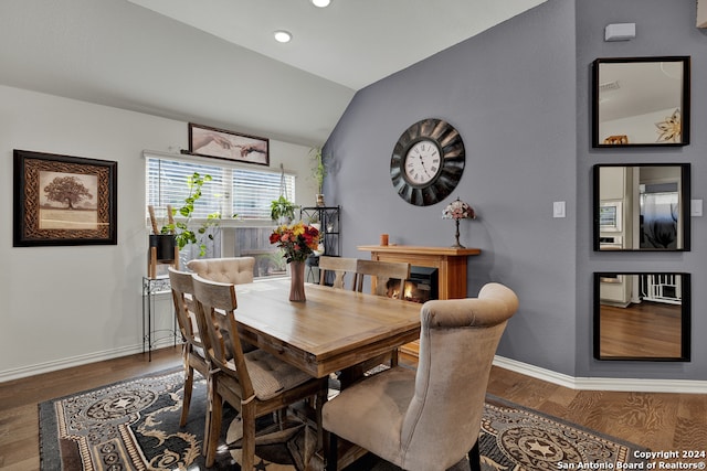 dining room with dark wood-type flooring and vaulted ceiling