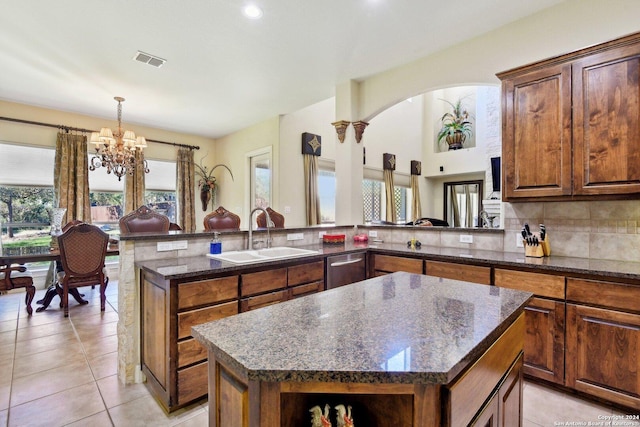 315 Dona Ana Cv, Helotes, TX 78023 - kitchen with a sink, a chandelier, dark stone counters, light tile patterned floors, and a peninsula