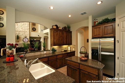 kitchen with backsplash, dark stone counters, sink, stainless steel fridge with ice dispenser, and kitchen peninsula