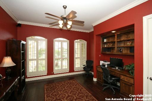 home office with ceiling fan, dark wood-type flooring, and ornamental molding