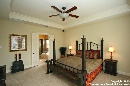 bedroom with a raised ceiling, ceiling fan, light colored carpet, and ornamental molding