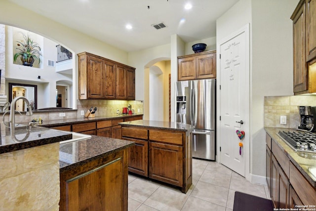 315 Dona Ana Cv, Helotes, TX 78023 - kitchen featuring appliances with stainless steel finishes, arched walkways, tasteful backsplash, dark stone counters, and a center island