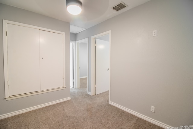 unfurnished bedroom featuring ceiling fan, light colored carpet, and a closet