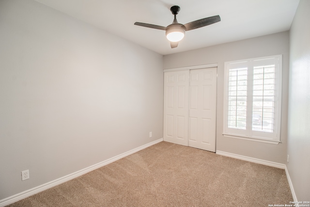 unfurnished bedroom featuring light carpet, a closet, and ceiling fan