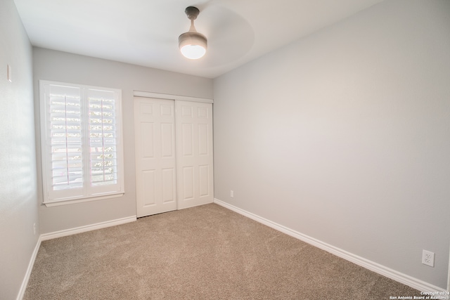 unfurnished bedroom featuring carpet flooring, ceiling fan, and a closet