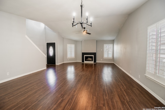 unfurnished living room featuring ceiling fan with notable chandelier, lofted ceiling, and dark wood-type flooring